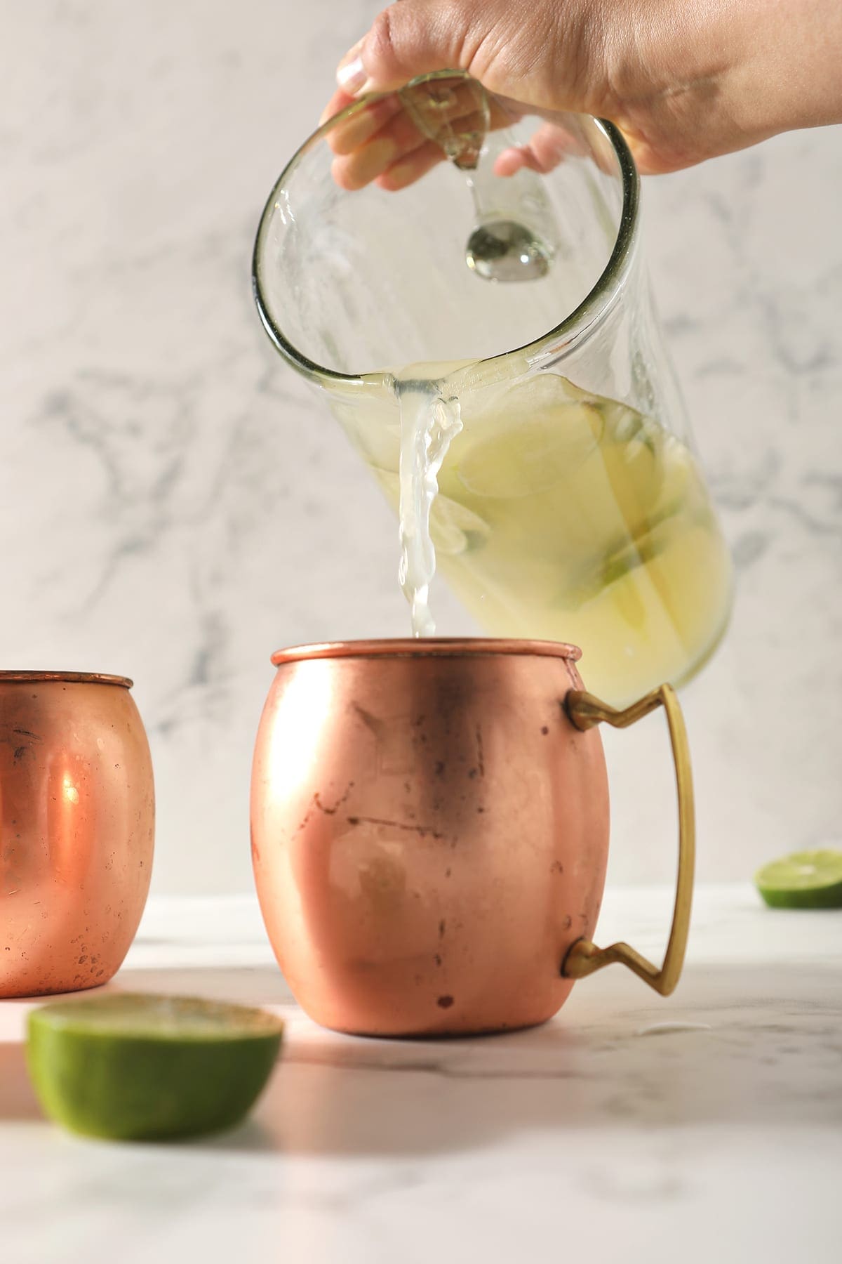 A pitcher pours liquid into a copper mug