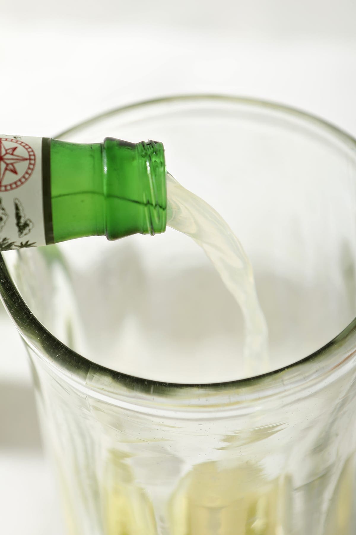 Ginger beer pours into a tall pitcher over vodka and lime juice