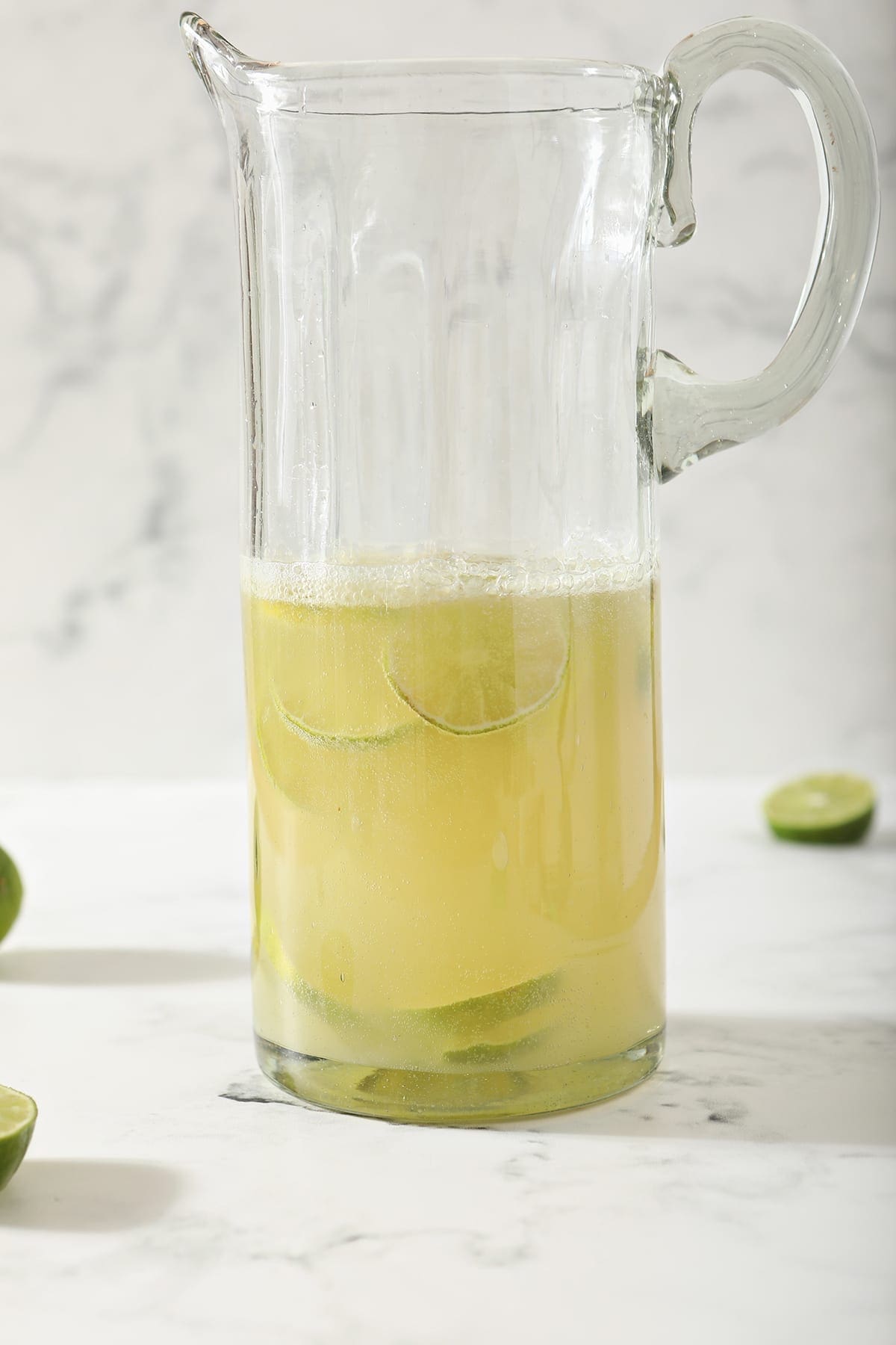 A Moscow Mule Pitcher with lime rounds inside the pitcher on marble