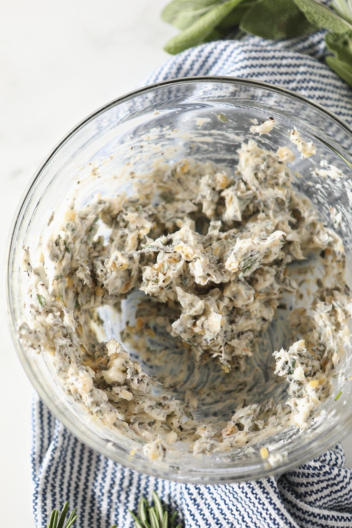 Blended herb butter in a bowl on top of a blue striped towel