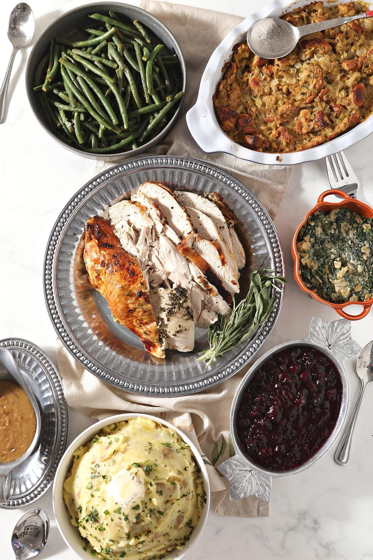 Roasted Herb Butter Turkey Breast surrounded by holiday side dishes on a marble table