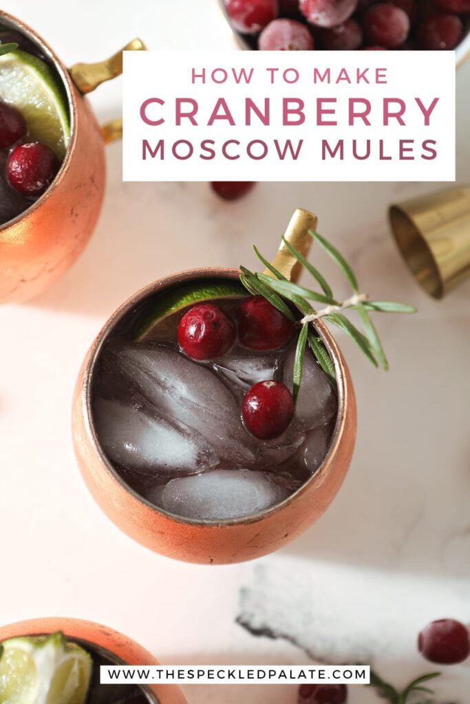 Close up of a copper mug holding a yule mule, garnished with a slice of lime, cranberries and a rosemary twig, with the text 'how to make cranberry moscow mules'