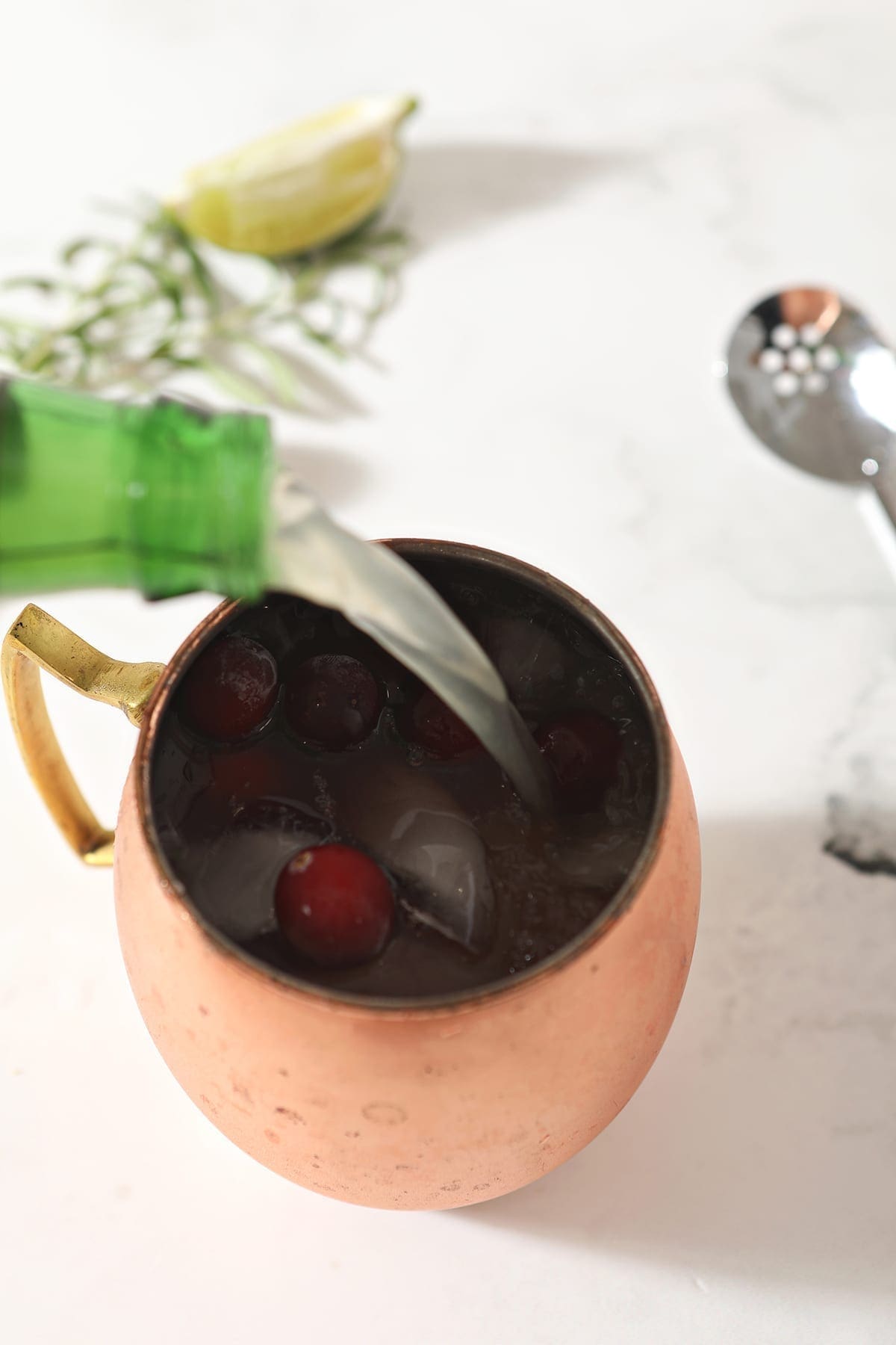 Ginger beer pours into a copper mug from above