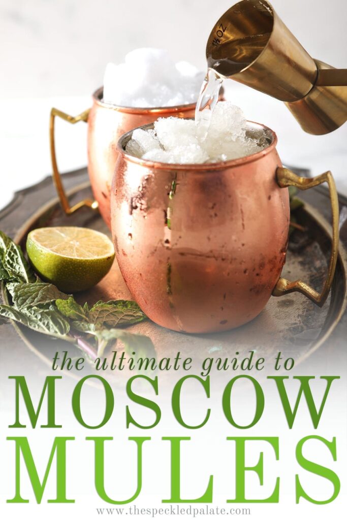 A gold jigger pours liquor into a copper mug filled with snow ice sitting on a silver tray next to mint sprigs and a lime wedge with the text 'the ultimate guide to moscow mules'