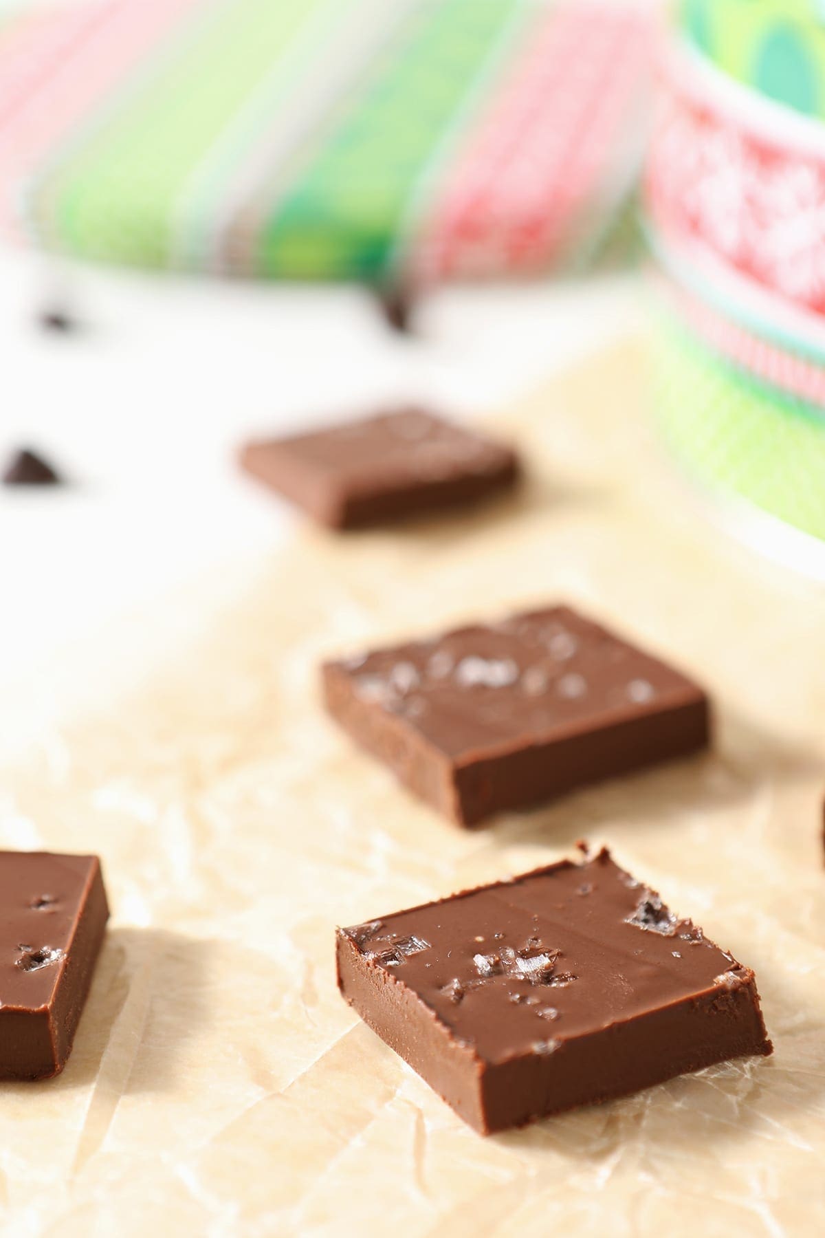 Sliced microwave fudge on parchment with a red and green patterned tin behind it