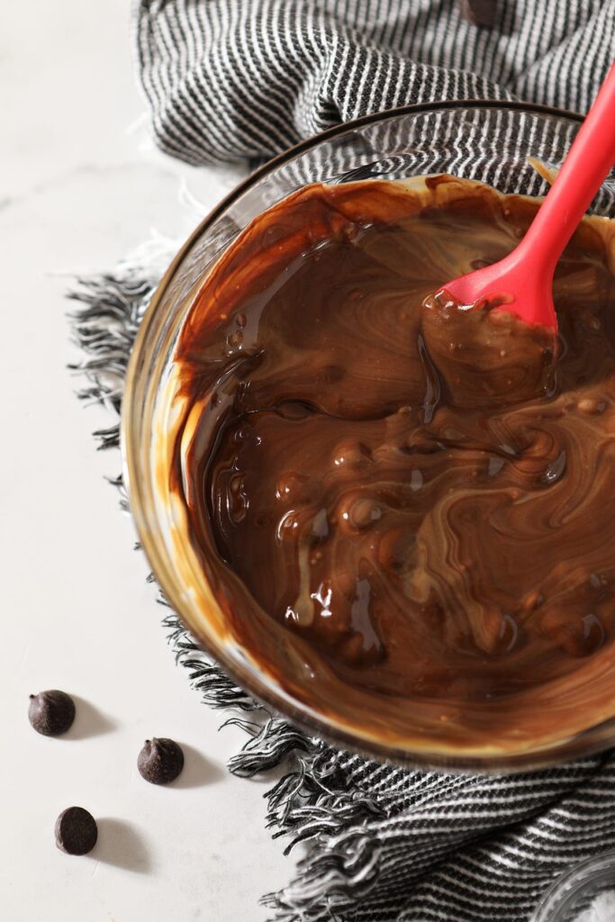 Close up of the melted peanut butter and chocolate in a glass bowl on top of a gray and white towel