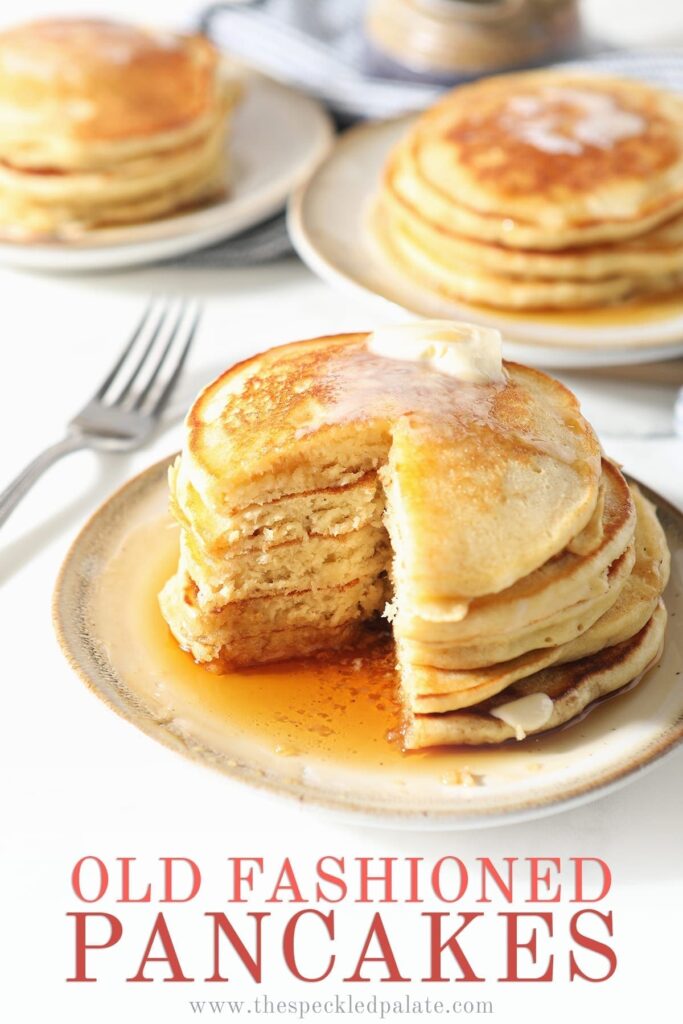 A stack of old fashioned homemade pancakes on a white plate with syrup and butter with a wedge cut out of it with the text 'old fashioned pancakes'