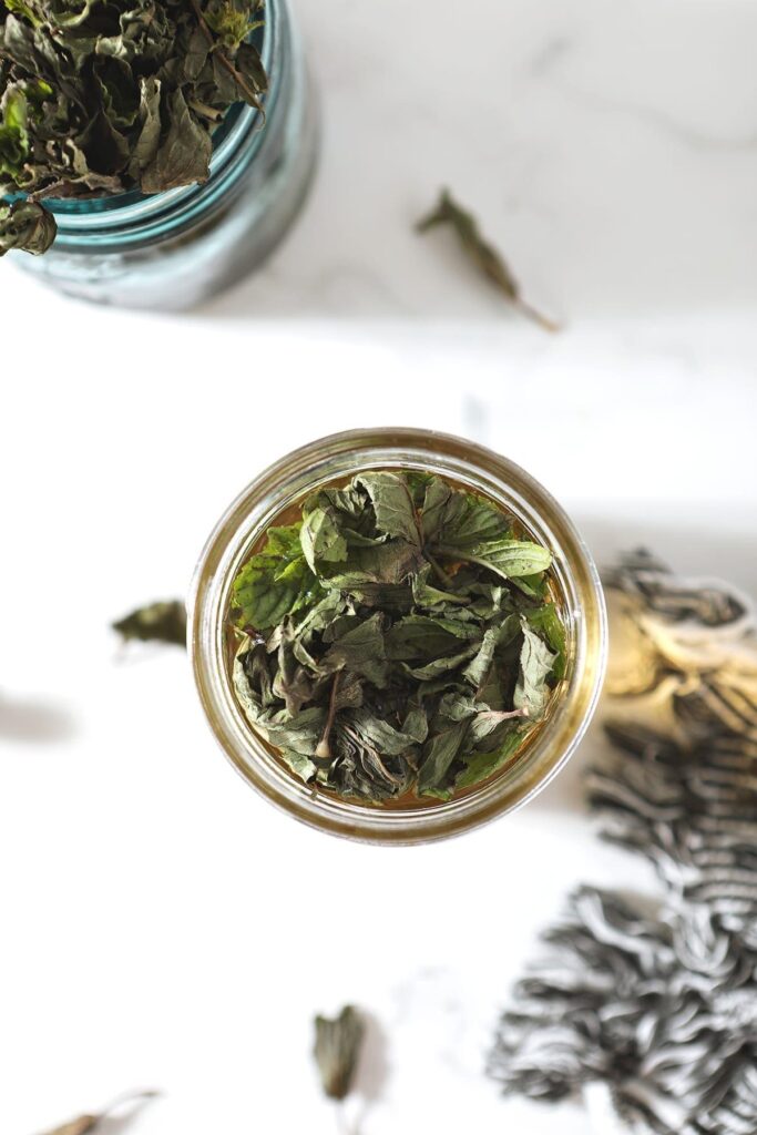 Mint leaves sit on top of a jar of simple syrup before being stirred in