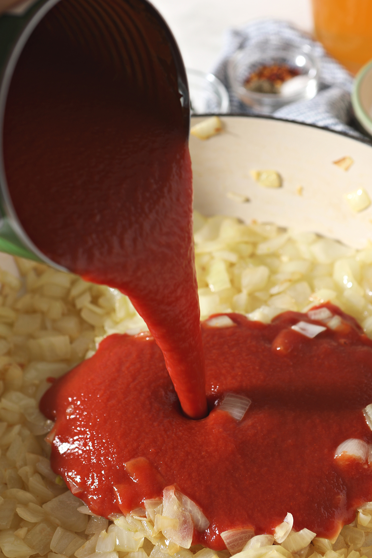 tomato puree pours into a large pot with sauteed onions and garlic