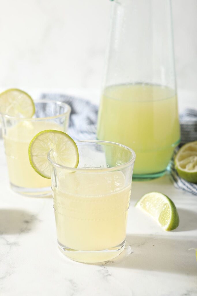 Two margaritas made from mix sit in front of a pitcher of homemade margarita mix