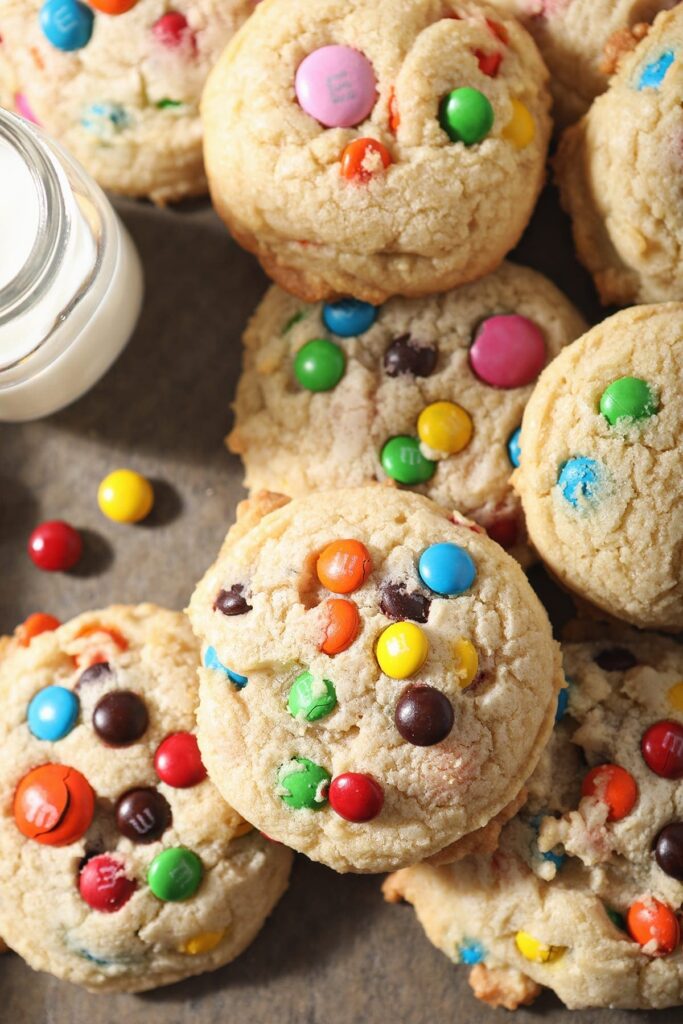 Close up of stacked M&M cookies next to a glass of milk