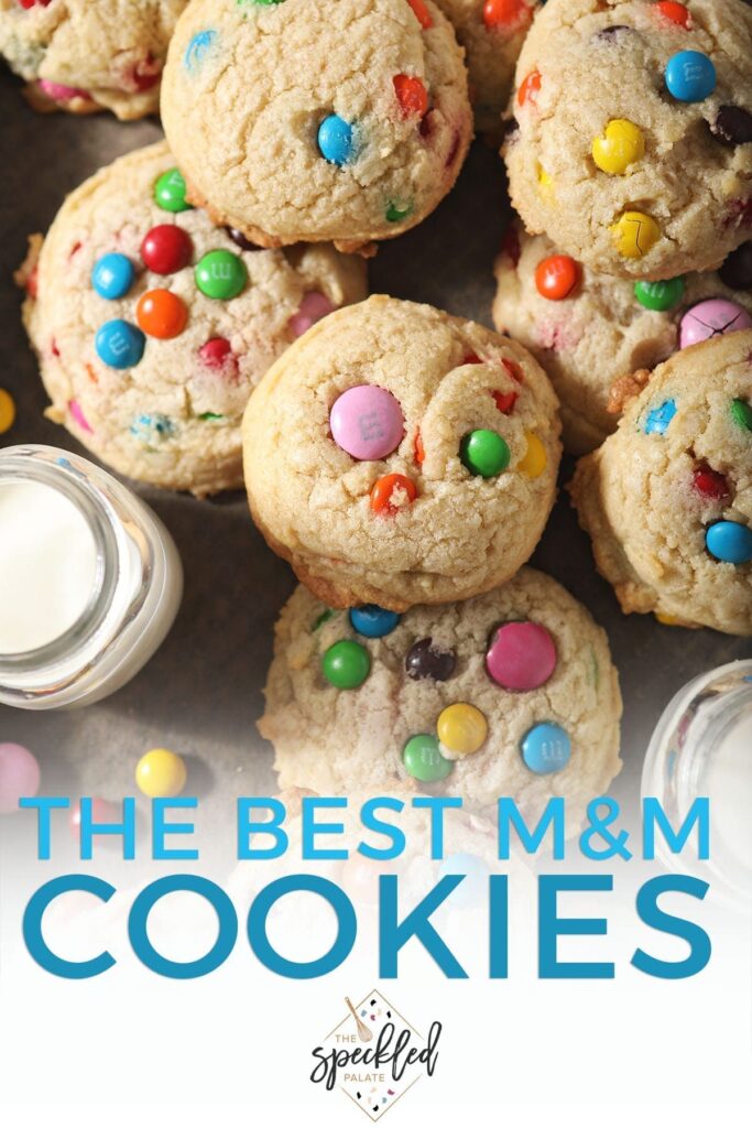 Close up of stacked M&M cookies next to a glass of milk with the text 'the best m&m cookies'