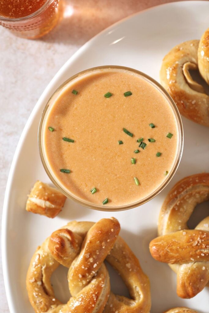 Close up of a bowl holding beer cheese dip next to pretzels