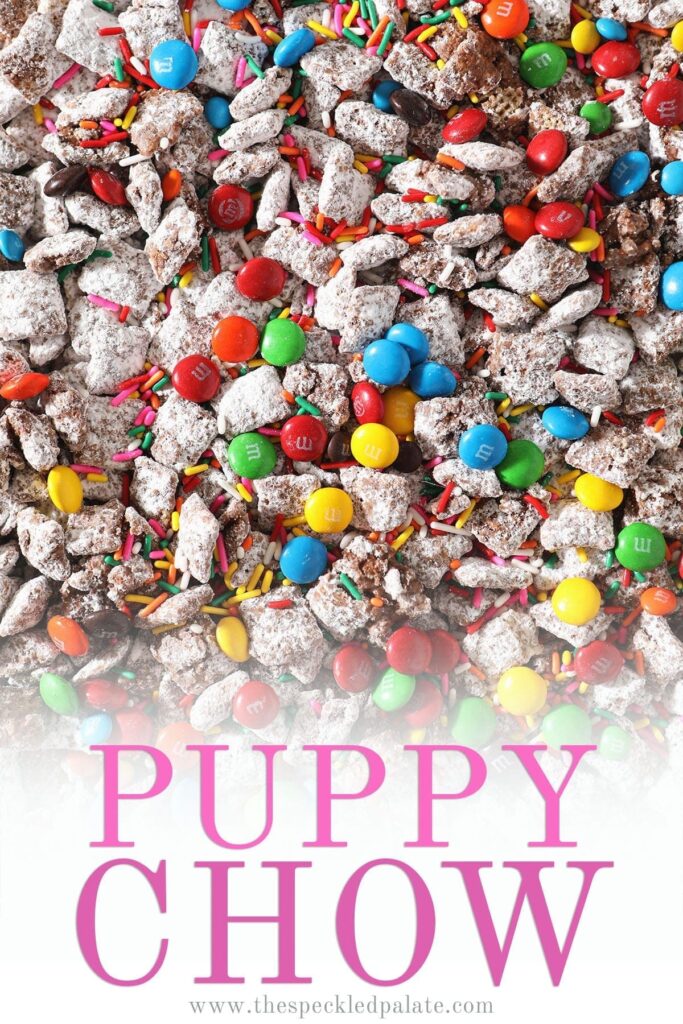 Close up of chocolate candies and sprinkles on top of a sweet snack mix with the text 'puppy chow'