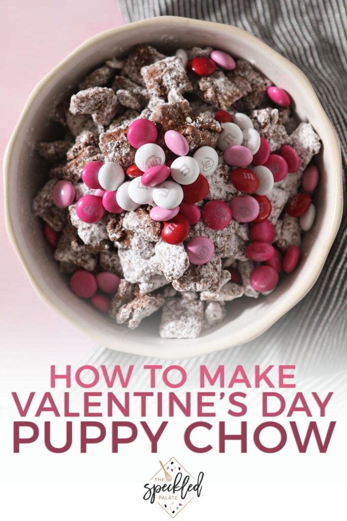 A bowl holding Puppy Chow with red, white and pink chocolate-coated candies with the text 'how to make valentine's day puppy chow'