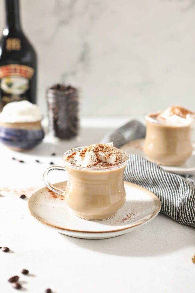 Two coffee drinks sit on pottery plates in front of ingredients