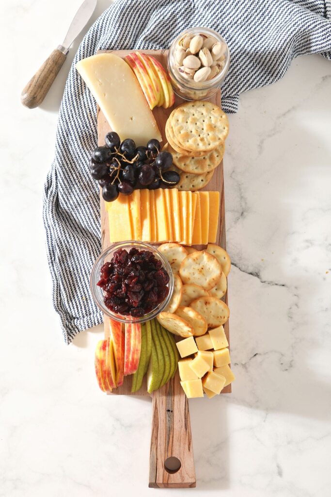 Fruit, cheese, crackers and other snacks on a wooden board