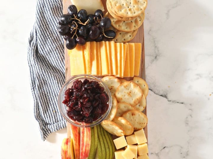 Fruit, cheese, crackers and other snacks on a wooden board