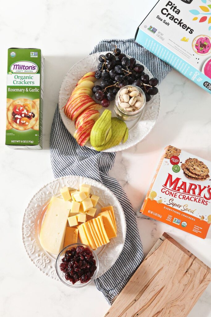 Cheeses, fruits and boxes of crackers on a blue striped towel