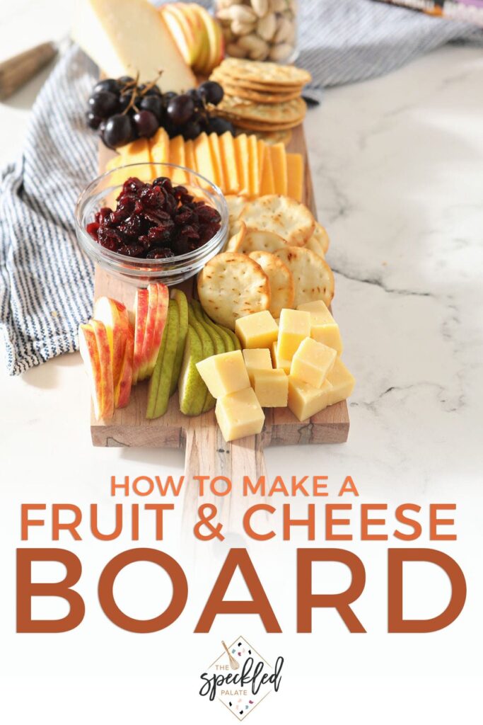 Stacked cheese cubes next to sliced fruit on a board with the text 'how to make a fruit & cheese board'