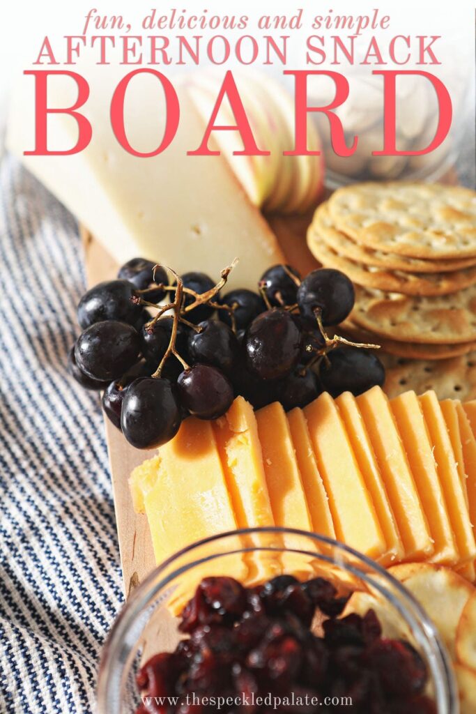 Grapes, cheese and crackers on a board with the text 'fun, delicious and simple afternoon snack board'