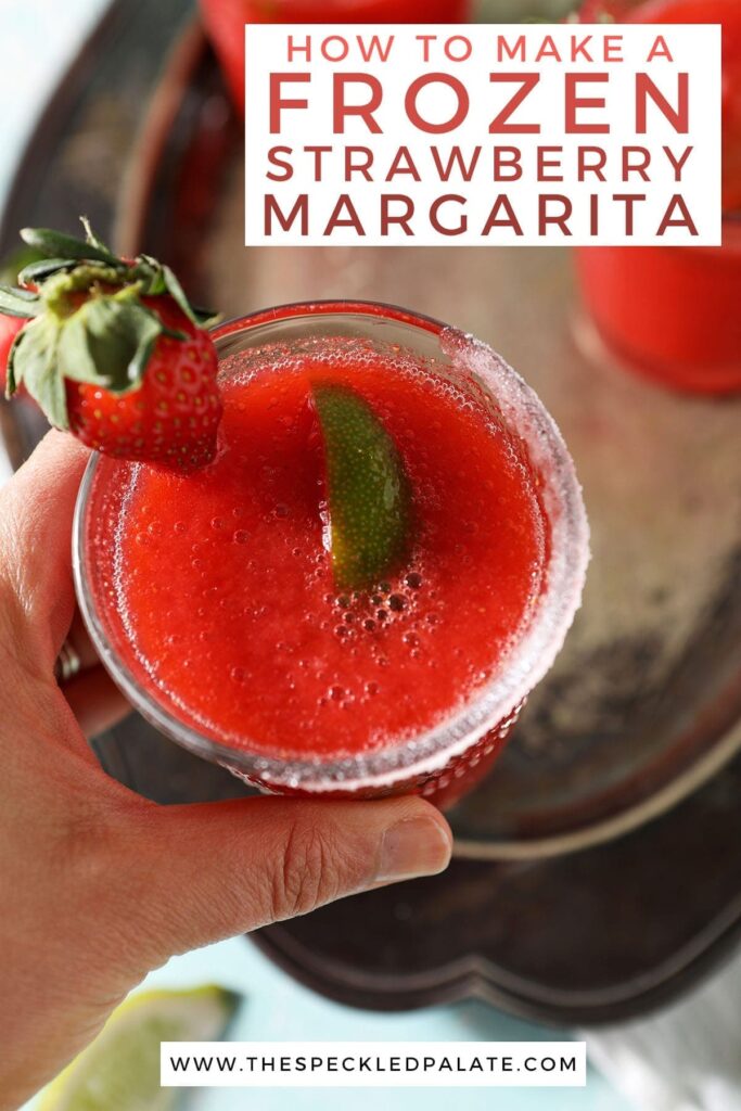 A woman holds a strawberry margarita garnished with a lime wedge and a strawberry with the text 'how to make a frozen strawberry margarita'