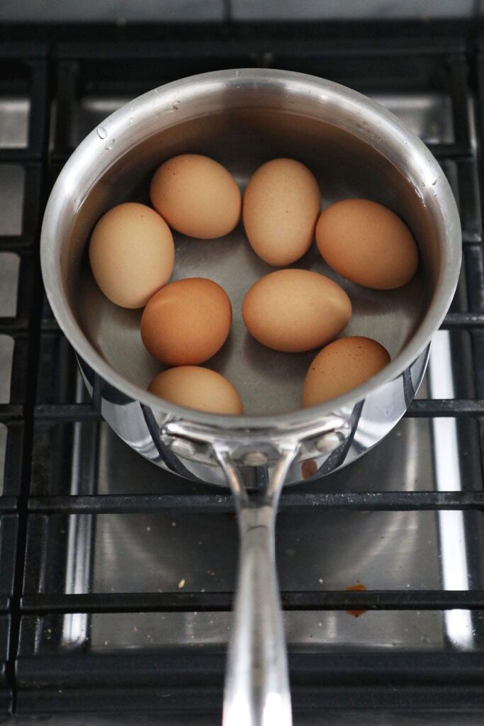 Eggs in water in a saucepan on a stovetop