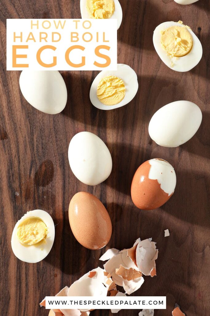 Hard boiled eggs are peeled on a dark wood cutting board with the text 'how to hard boil eggs'