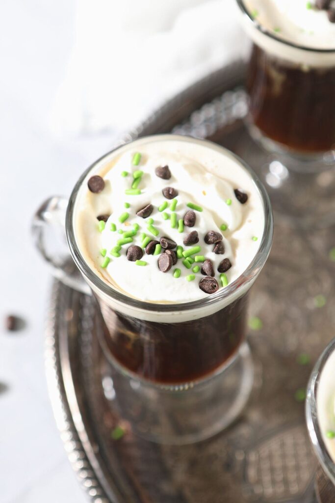 Close up of a coffee cocktail with whipped cream on top of it on a silver tray