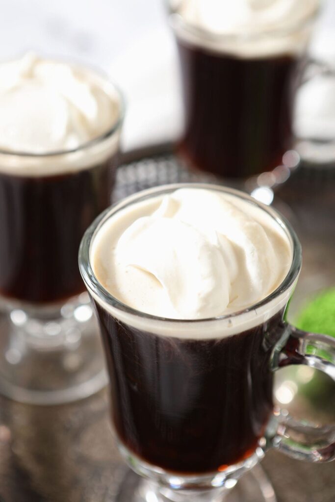 Sweetened whipped cream sits on top of coffee in a mug