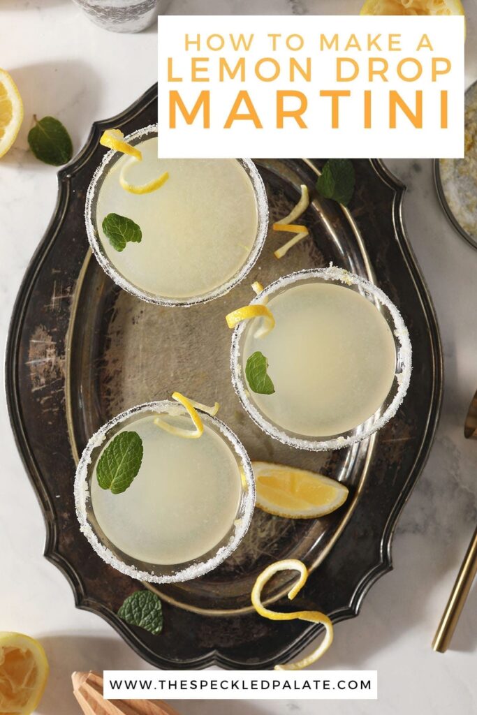 Three Lemon Drop Martinis garnished with mint leaves and lemon twists sit on a silver tray with the text 'how to make a lemon drop martini'