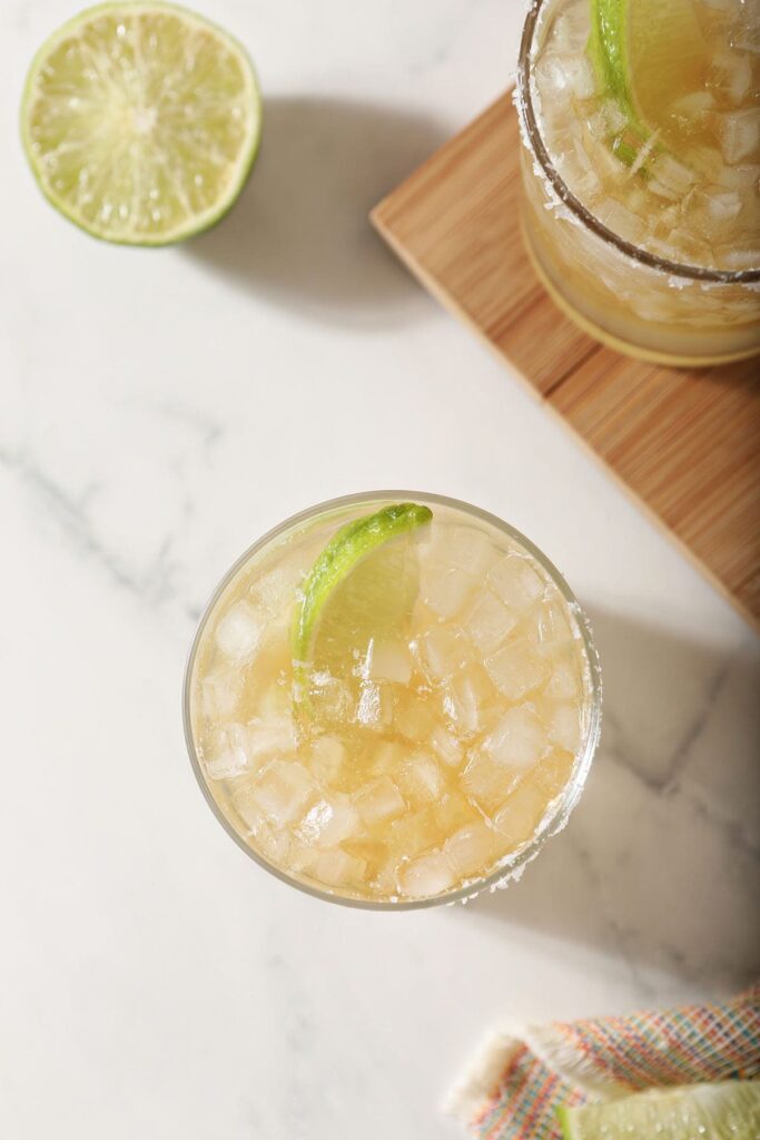 A top shelf margarita garnished with a lime on marble