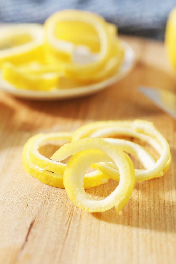 A pile of lemon twists on a wooden cutting board