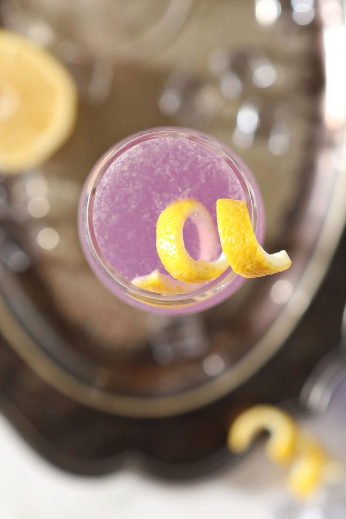 A cocktail twist sits on top of a purple drink