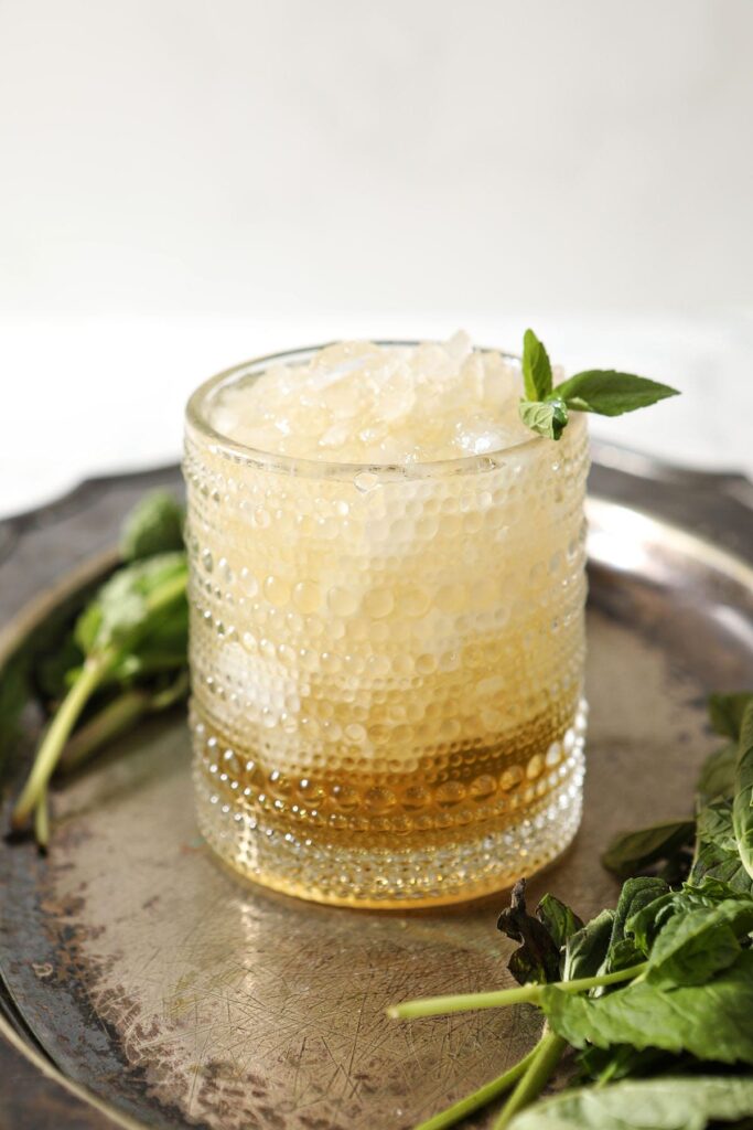 A mint julep on a silver tray with a mint garnish