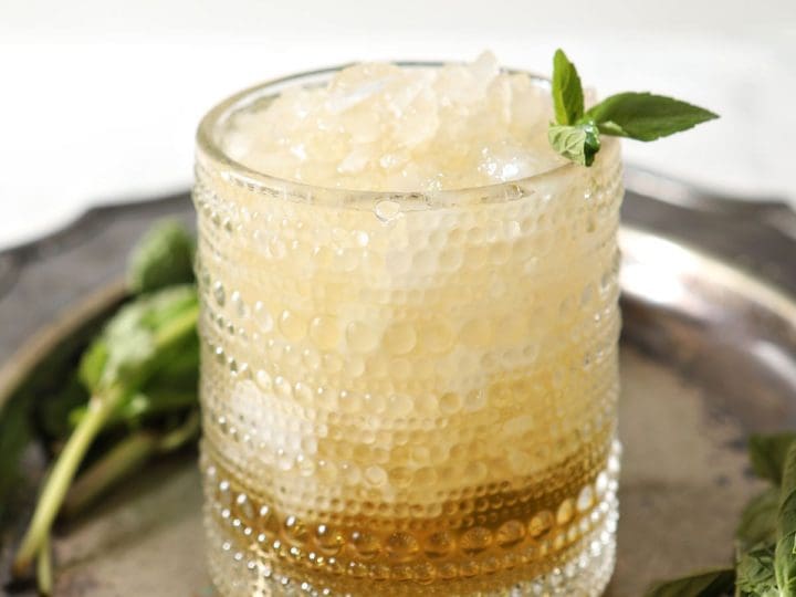 A mint julep on a silver tray with a mint garnish