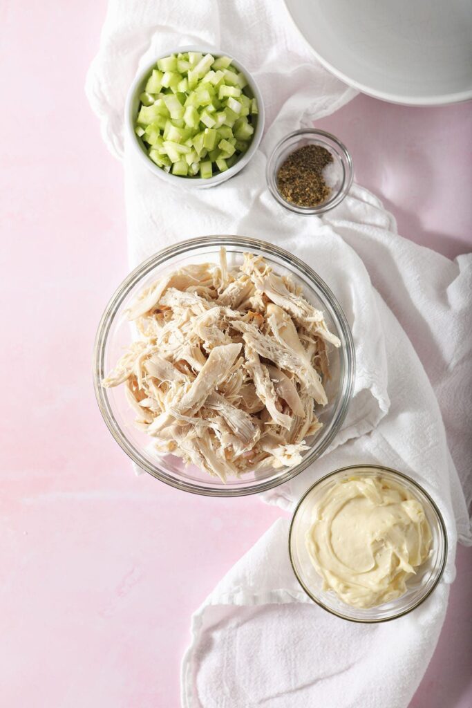 Bowls holding chicken, mayonnaise, celery and spices