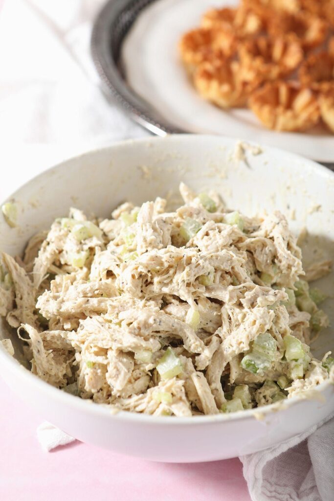 A bowl of chicken salad in front of phyllo cups