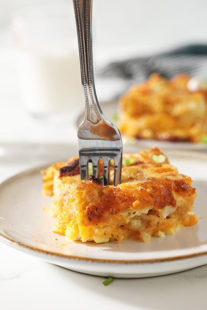 A fork cuts into a slice of breakfast tater tot casserole