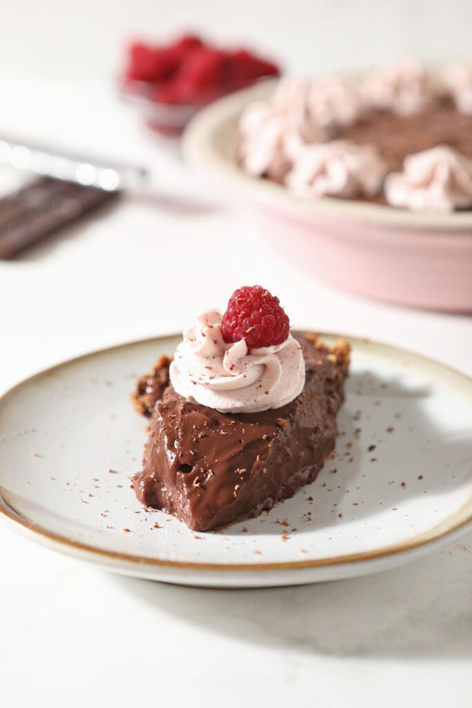 A slice of chocolate pudding pie with graham cracker pie crust on a plate