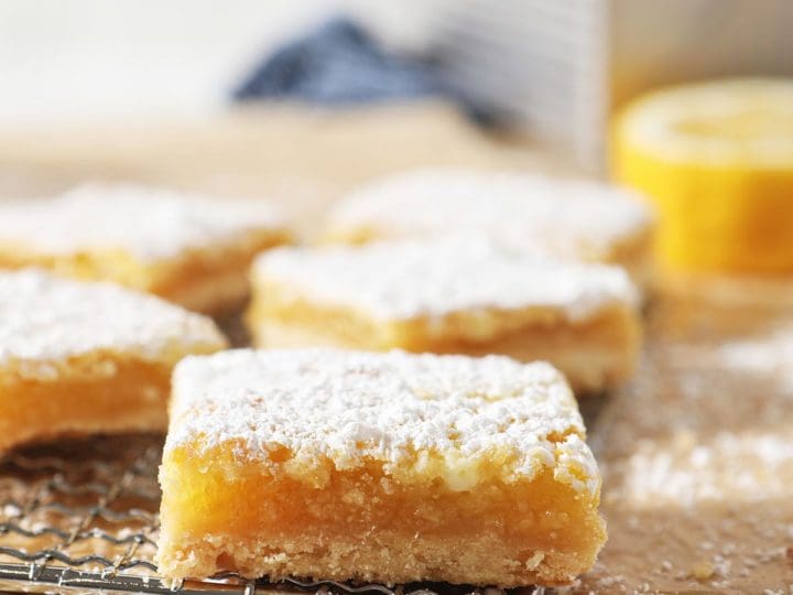 A lemon bar sits on a metal grate with other lemon bars