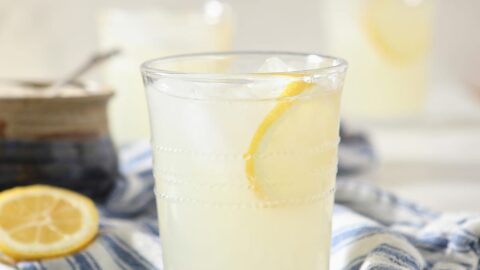 A glass of fresh squeezed lemonade garnished with a lemon round on a blue and white towel
