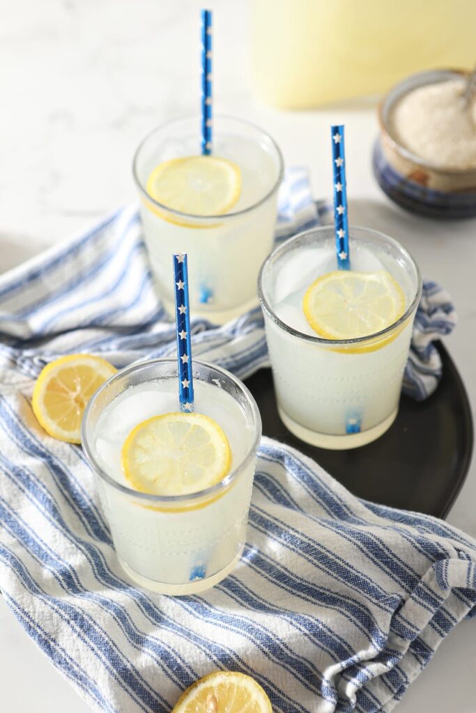 Three glasses of homemade lemonade on a blue and white towel