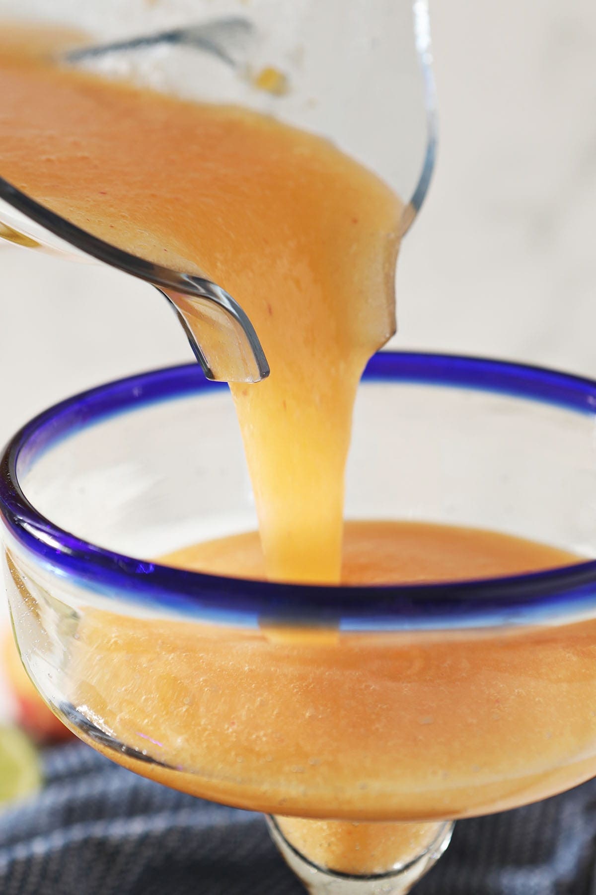  Peach margarita is poured from a blender into a margarita glass
