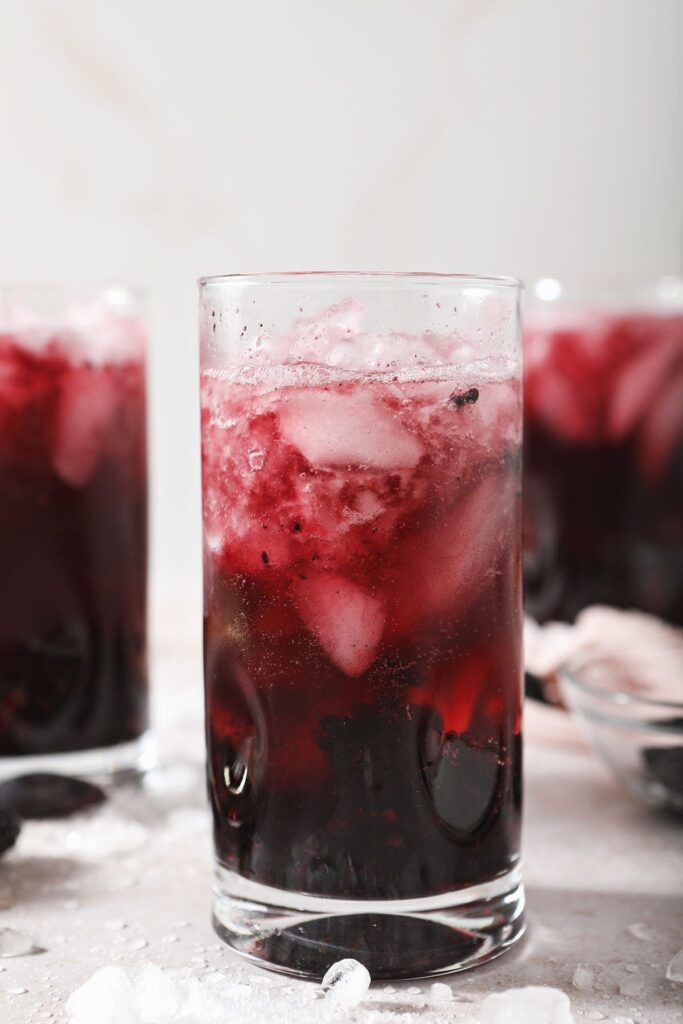 Three glasses of a red wine spritzer with ice