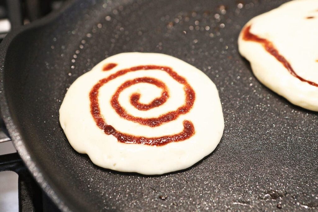 A cinnamon swirl inside a pancake on a skillet