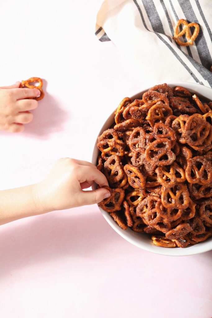 Two children reach and grab Cinnamon Sugar Pretzels from a bowl