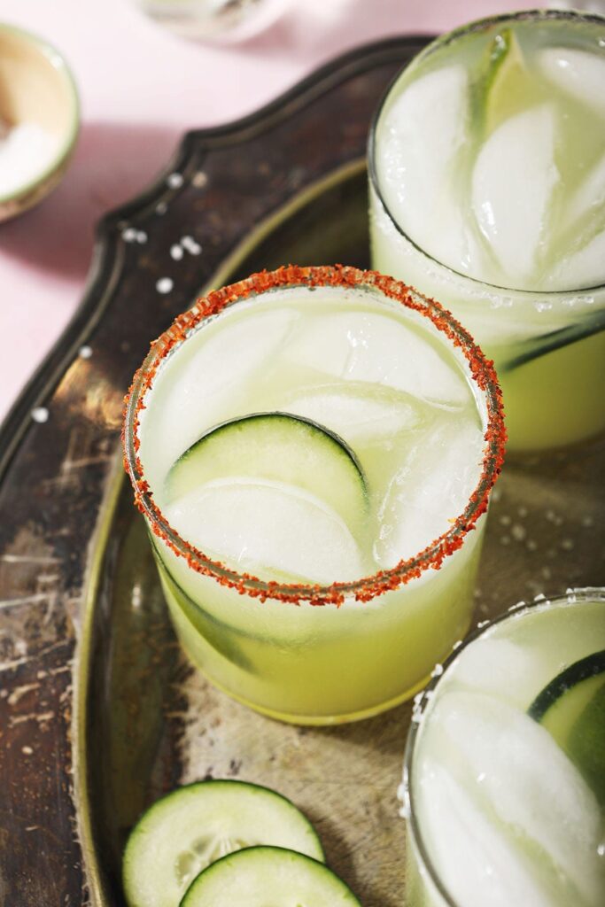 Three margaritas with cucumber on the rocks on a silver tray