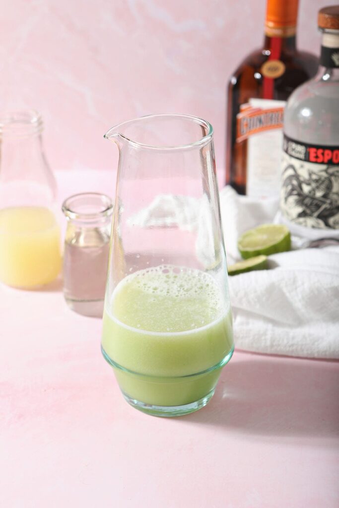 Ingredients for a cucumber margarita on pink tile