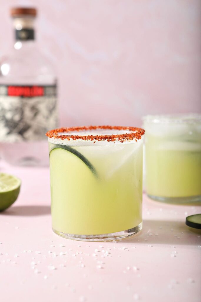 A cucumber margarita on a pink countertop